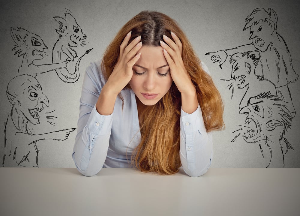 Evil Men pointing at stressed woman. Desperate young businesswoman sitting at desk in her office isolated on grey wall background. Negative human emotions face expression feelings life perception Evil Men pointing at stressed woman. Desperate young businesswoman sitting at desk in her office isolated on grey wall background. Negative human emotions face expression feelings life perception